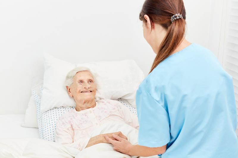 old_women_hospice_nursing_home_being_comforted_nurse_old_woman_bed